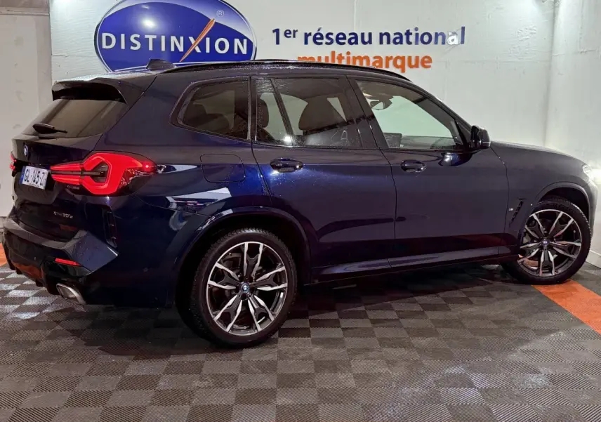 BMW X3 xDrive30e bleu en vue profil droit, avec jantes alliage et feux arrière LED distinctifs.
