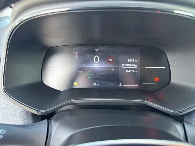 Vue rapprochée du compteur numérique 7 pouces de la Renault Clio V blanc, affichant la vitesse à 0 km/h et divers indicateurs.