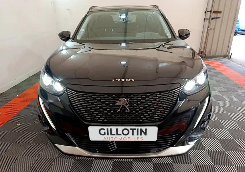 Peugeot 2008 noir vue de face en intérieur, phares LED allumés et calandre distinctive avec logo lion.