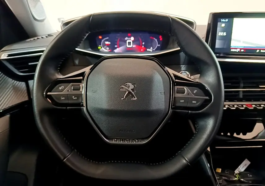 Vue rapprochée du volant cuir noir de la Peugeot 2008 avec commandes intégrées et tableau de bord numérique lumineux.
