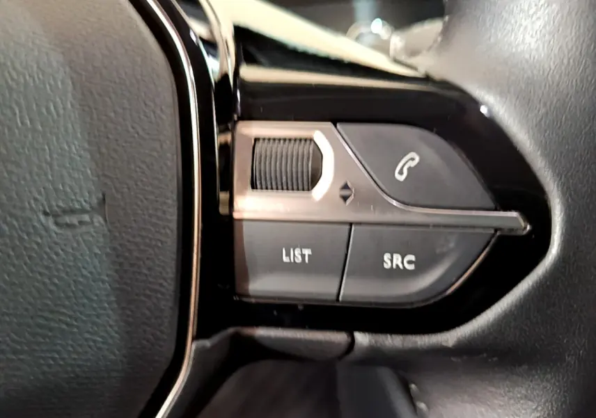 Gros plan sur les commandes du volant noir du Peugeot 2008 PureTech 130 S&S Allure Business 2021, boutons appel et liste.
