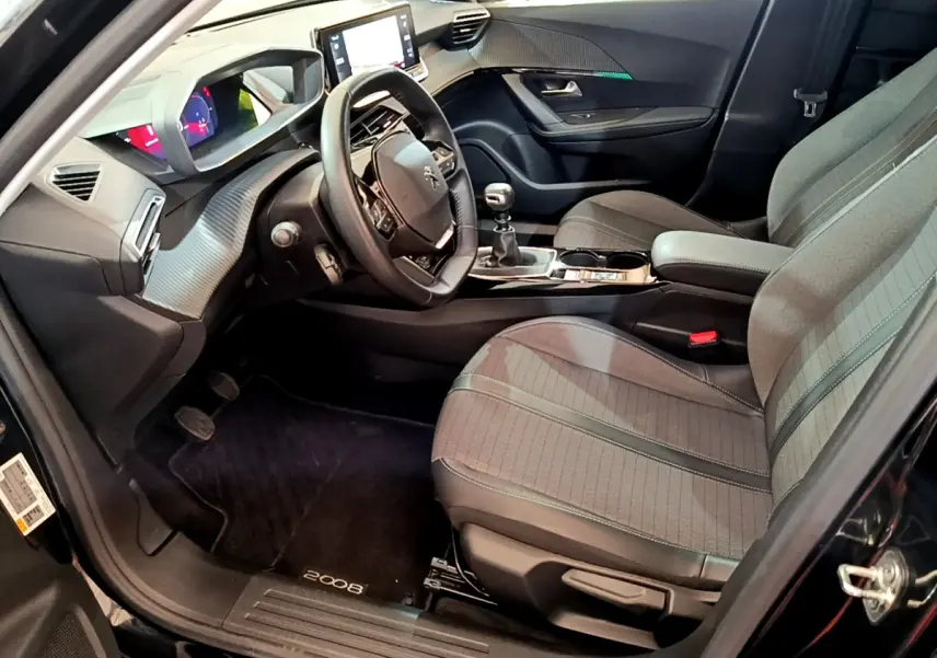 Intérieur avant droit du Peugeot 2008 noir 2021, volant cuir, écran tactile 10 pouces et boîte manuelle visible.