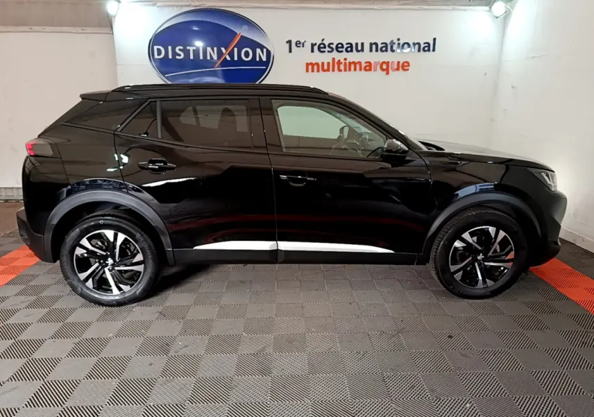 Profil latéral droit d'un Peugeot 2008 noir 2021 avec jantes alliage et protections noires sur les passages de roues.