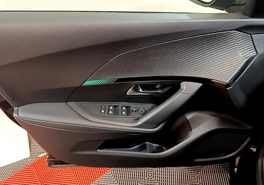 Vue rapprochée de la porte côté gauche du Peugeot 2008 noir, avec insert décoratif effet carbone et commandes électriques.