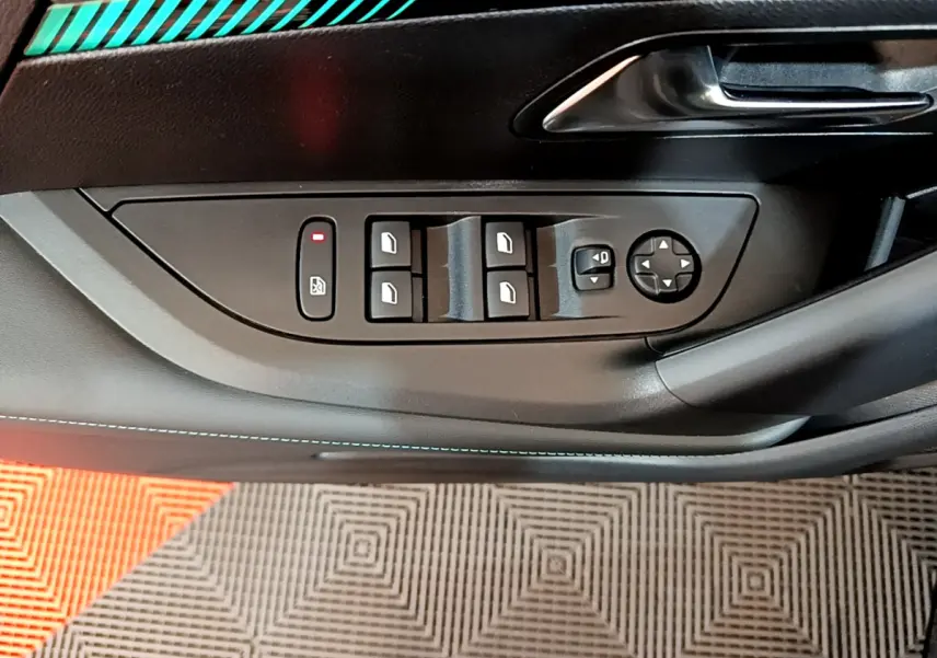 Gros plan sur la commande des vitres électriques côté conducteur du Peugeot 2008 noir, avec poignée de porte métallique.