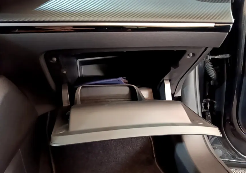 Gros plan sur la boîte à gants ouverte côté passager du Peugeot 2008 noir, montrant un rangement intérieur.