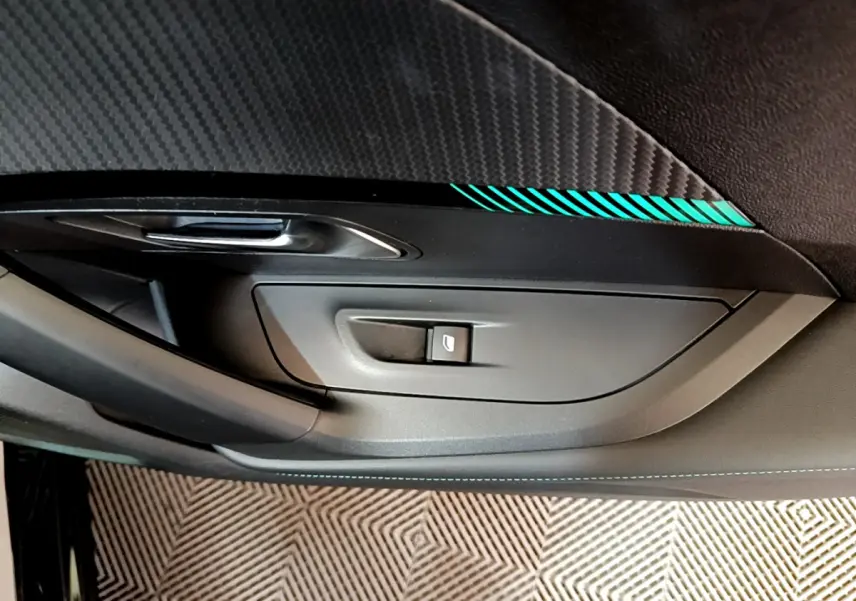 Détail de la porte côté gauche intérieure noire avec bouton de lève-vitre et insert décoratif bleu sur Peugeot 2008 2021.