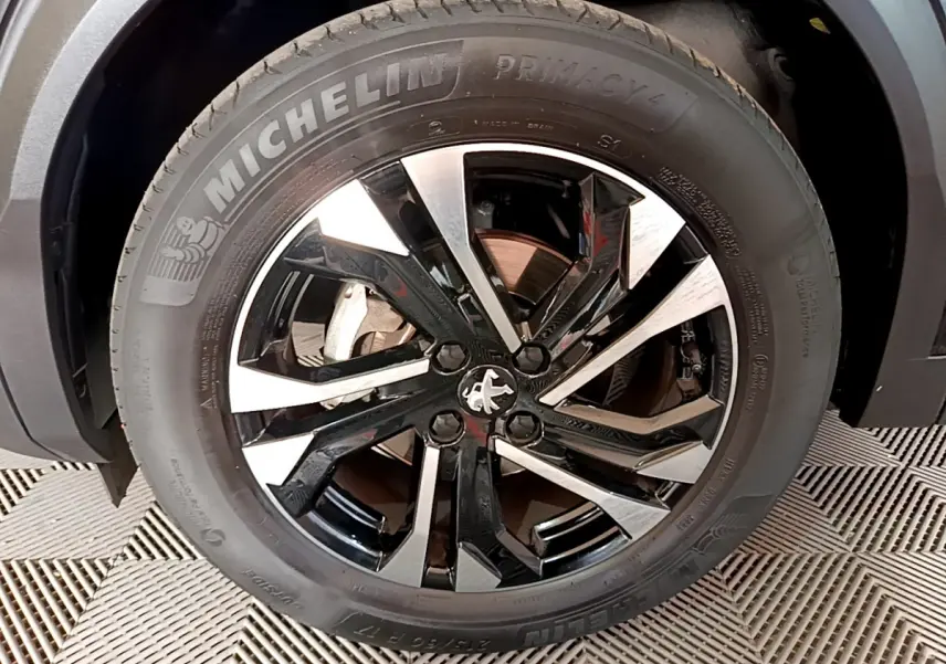 Gros plan sur la jante noire et argentée d’un Peugeot 2008 PureTech 130 S&S Allure Business noir avec pneu Michelin Primacy 4.