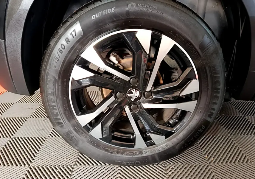 Gros plan sur la jante noire et argentée d'une Peugeot 2008 PureTech 130 S&S Allure Business noire, pneu Michelin visible.