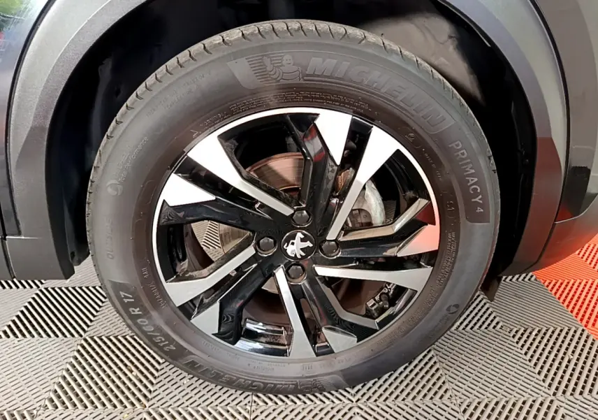 Gros plan sur la jante noire et argentée d'une Peugeot 2008 PureTech 130, avec pneu Michelin Primacy 4 visible.