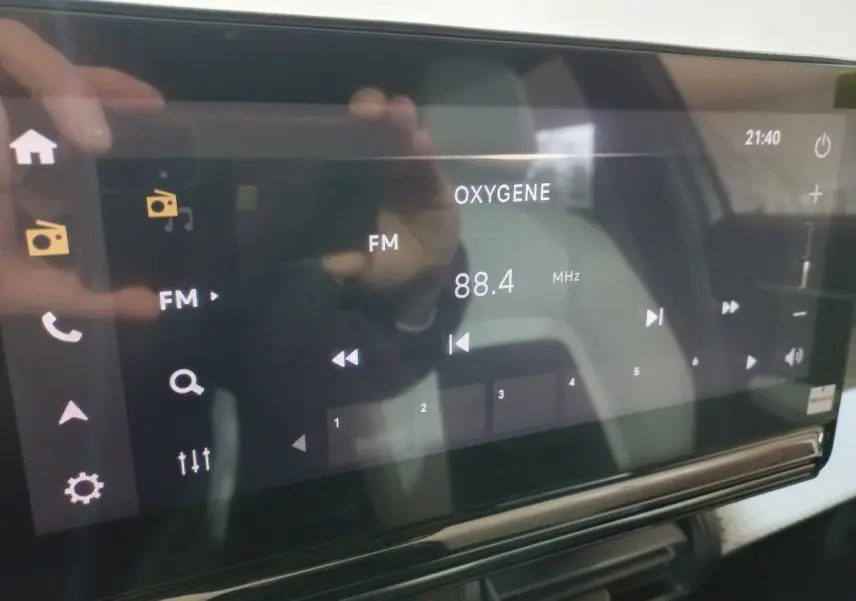 Écran tactile central de la Citroën C3 hybride 2025 affichant la radio FM sur fond noir, intérieur gris visible.