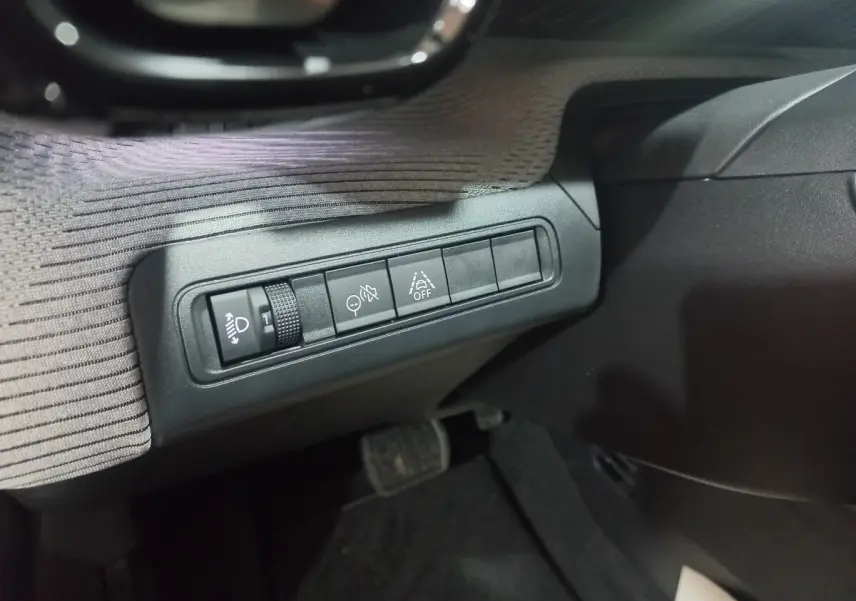 Gros plan sur les commandes d’aide à la conduite à gauche du volant dans l’habitacle gris foncé du Citroën C3 hybride 2025.