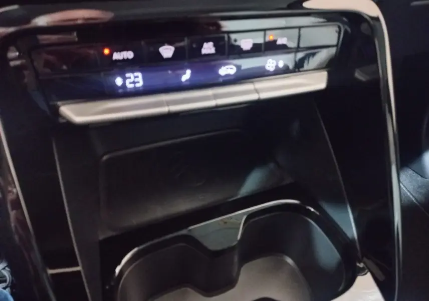 Gros plan sur la console centrale de la Citroën C3 hybride 2025 gris foncé, avec zone de recharge par induction et commandes tactiles.