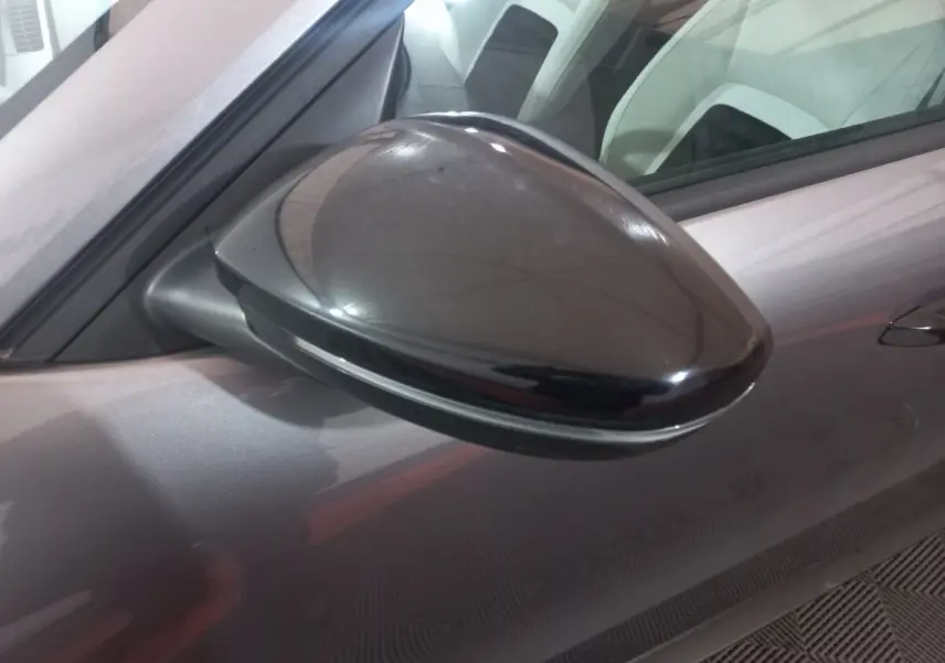 Rétroviseur côté gauche noir brillant de la Citroën C3 hybride gris foncé, vue rapprochée sur la portière avant.