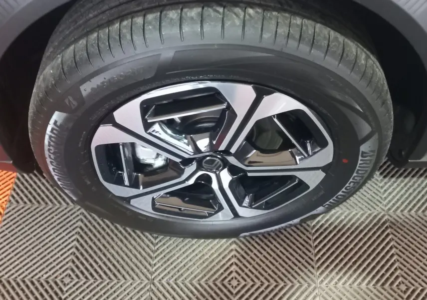 Gros plan sur la roue avant droite de la Citroën C3 hybride 2025, jante bicolore noir et argent, pneu Bridgestone.