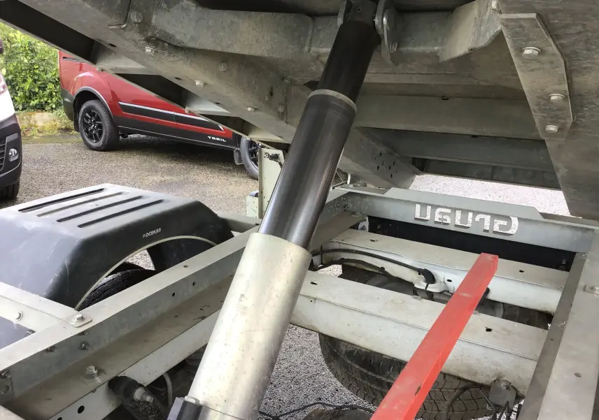 Gros plan sous la benne du Ford Transit Chassis Cabine blanc, montrant le vérin hydraulique et le châssis métallique.