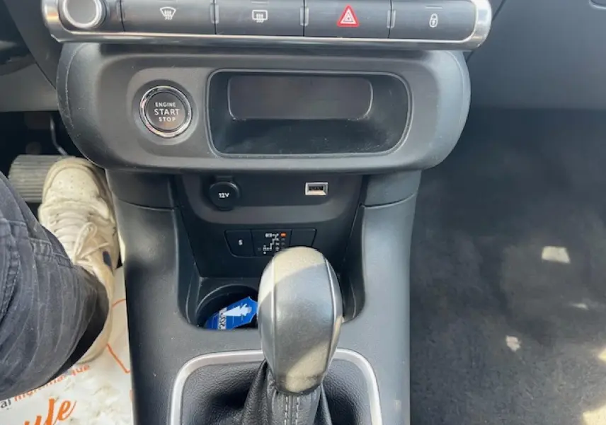 Gros plan sur la console centrale noire de la Citroën C3 2023, avec levier de boîte automatique et bouton start/stop.
