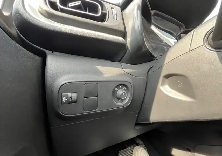Détail des commandes de réglage des rétroviseurs côté gauche dans l'habitacle noir d'une Citroën C3 2023.