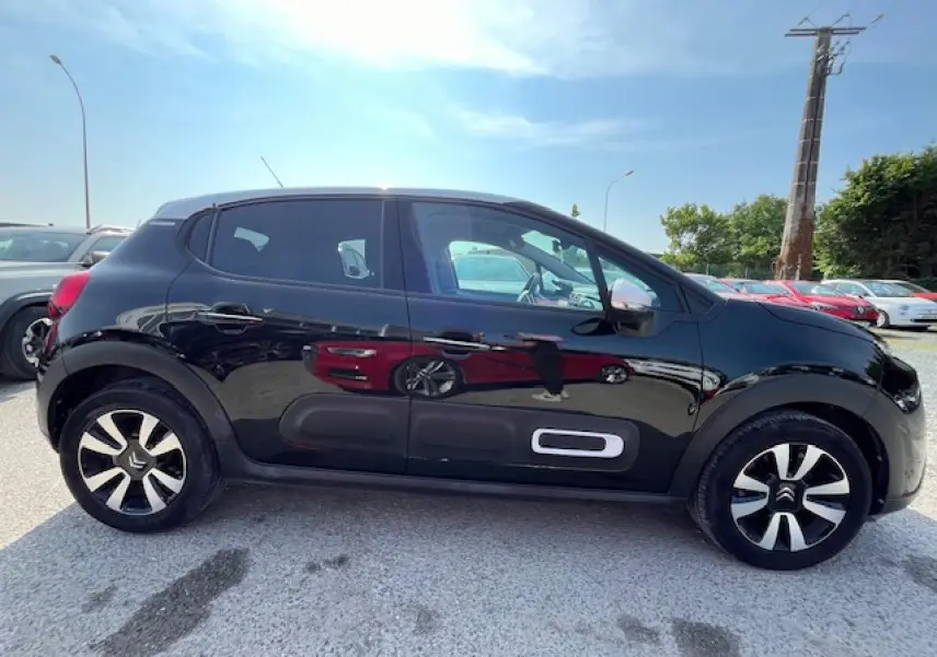 Profil latéral gauche d'une Citroën C3 noire 2023 avec jantes alliage et protections latérales caractéristiques.