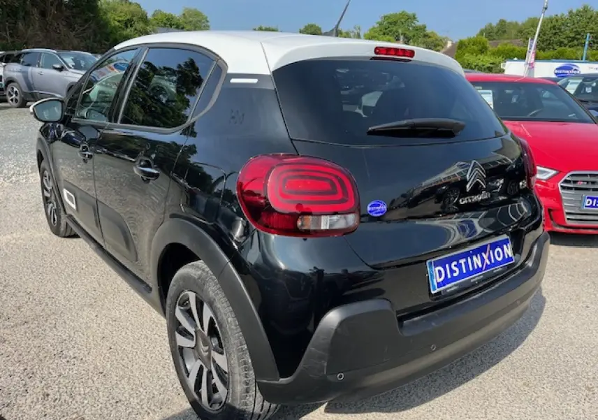 Vue 3/4 arrière gauche d'une Citroën C3 noire avec toit blanc et jantes alliage 16 pouces diamantées.