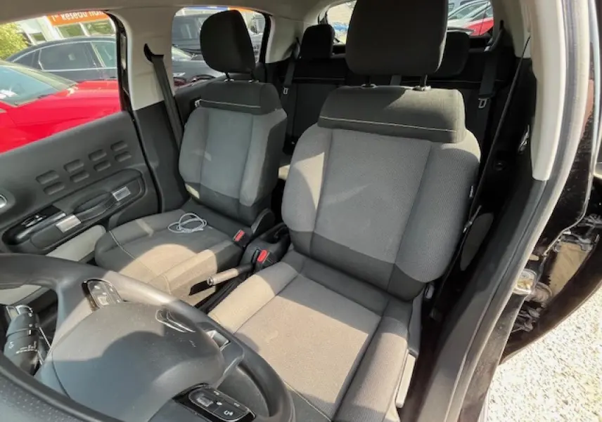 Vue intérieure côté conducteur d'une Citroën C3 noire 2023, mettant en valeur les sièges tissu gris et le volant multifonction.