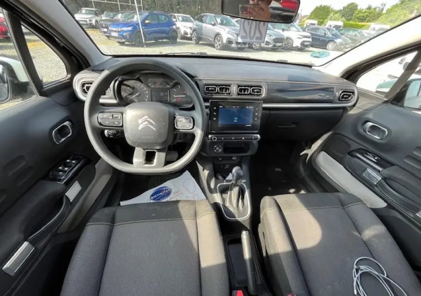 Vue intérieure avant de la Citroën C3 noire 2023, tableau de bord moderne avec écran tactile et volant multifonction.