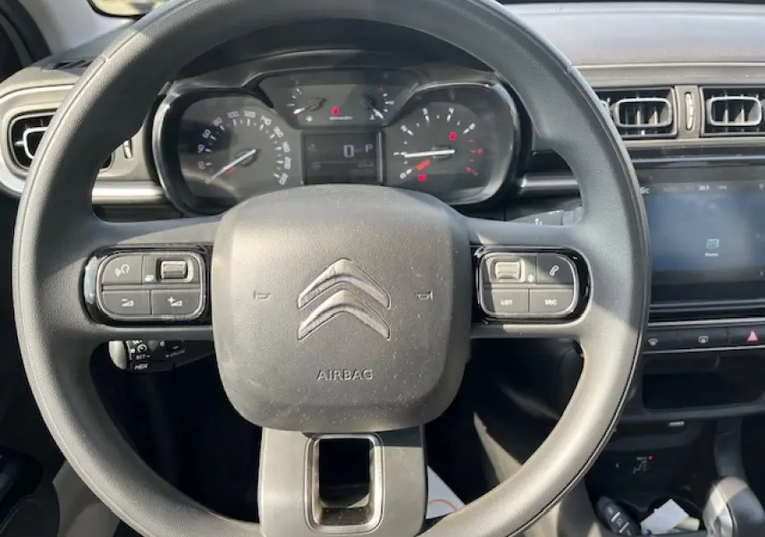 Vue rapprochée du volant noir de la Citroën C3 2023 avec commandes intégrées et tableau de bord digital.