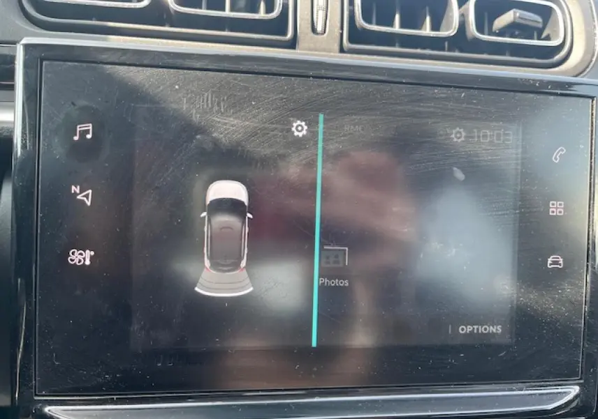 Écran tactile central du tableau de bord d'une Citroën C3 noire 2023 montrant l'aide au stationnement avec vue aérienne du véhicule.