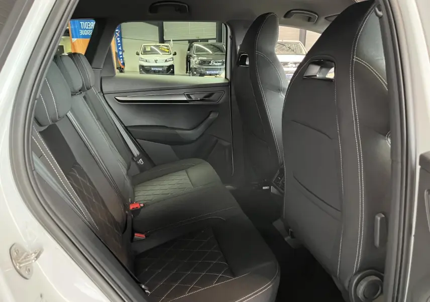 Vue côté gauche de l'intérieur arrière du SKODA KAROQ blanc avec sièges noirs et surpiqûres contrastées.