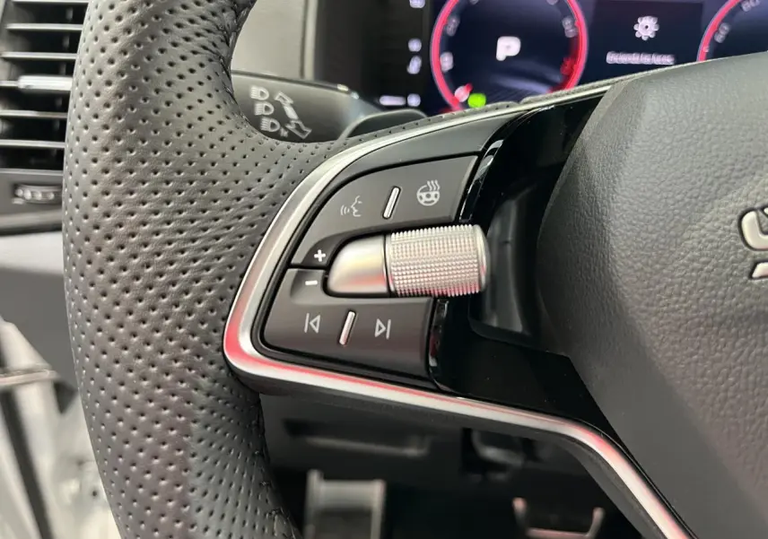 Gros plan sur les commandes du volant cuir perforé noir du Skoda Karoq 2025 avec molette métallique et tableau de bord digital.