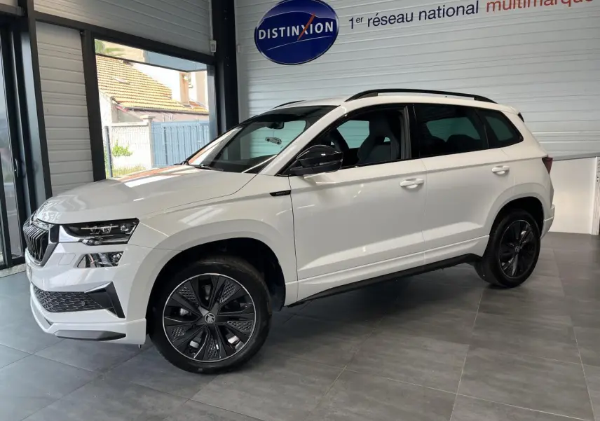 SUV SKODA KAROQ blanc vue de côté droit en intérieur avec jantes noires et toit noir Sportline