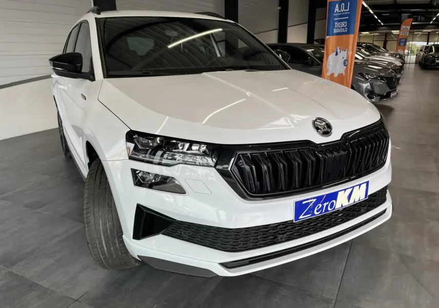 SUV SKODA KAROQ blanc en 3/4 avant droit avec calandre noire et phares LED dans un showroom.