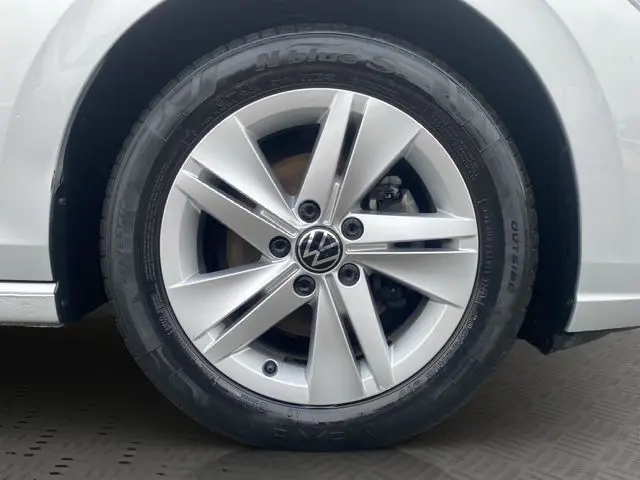 Gros plan sur la roue avant gauche d'une Volkswagen Golf VIII gris argent, mettant en valeur la jante alliage et le logo VW central.