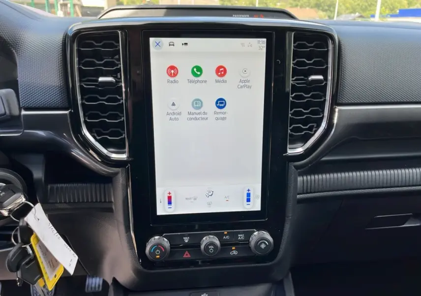 Vue rapprochée de la console centrale tactile du Ford Ranger blanc glacier 2025 avec commandes climatisation et connectivité Apple CarPlay.