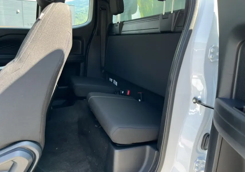 Vue intérieure côté droit du Ford Ranger 2025 blanc glacier, montrant la banquette arrière compacte et les sièges avant en tissu noir.
