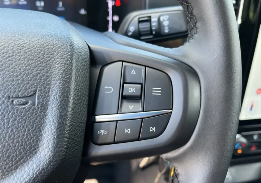 Gros plan sur les commandes multifonctions à droite du volant du Ford Ranger blanc glacier 2025, version XLT SuperCab.