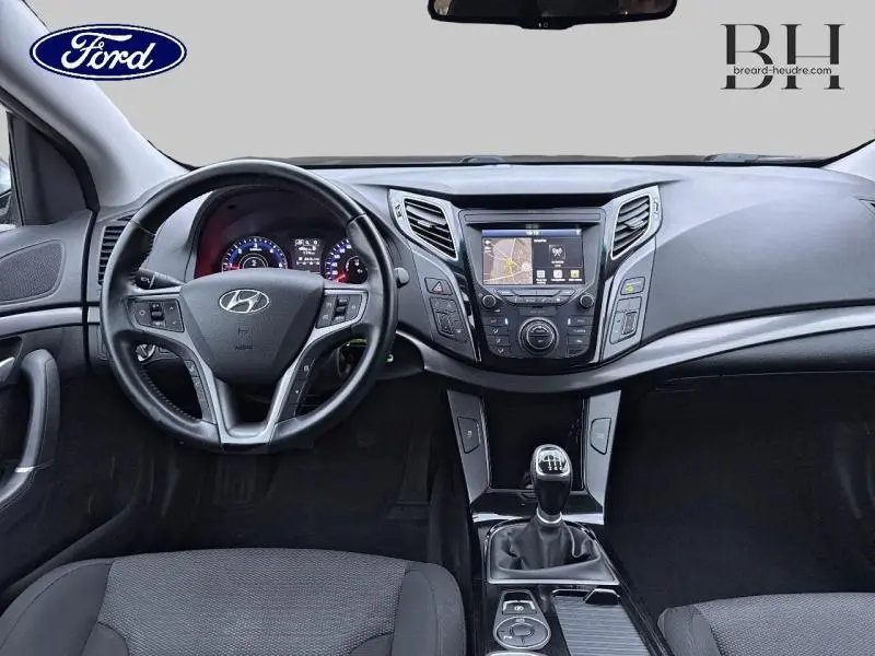 Tableau de bord et volant cuir d'une Hyundai i40 SW 2017, vue frontale intérieure avec écran tactile et levier manuel.