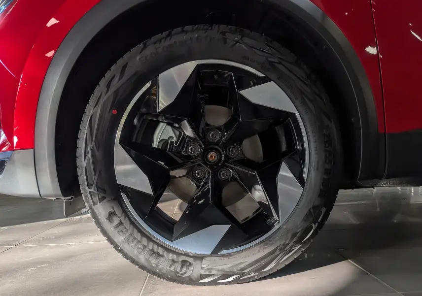 Gros plan sur la roue avant droite du Renault Captur rouge Flamme avec jante noire et argentée au design géométrique.