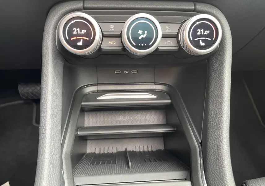 Vue rapprochée de la console centrale du Skoda Kodiaq 2024, avec commandes climatisation et zone de rangement marquée KODIAQ.