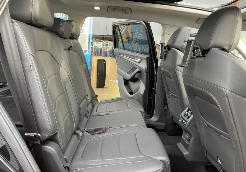 Vue intérieure côté gauche du Skoda Kodiaq noir métal 2024, montrant les sièges arrière en cuir noir et la porte ouverte.