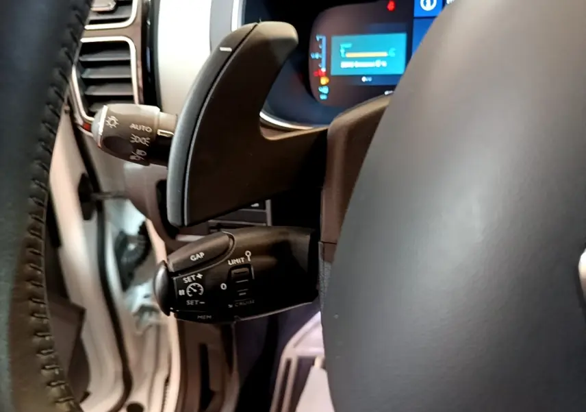 Gros plan sur la commande multifonctions du volant cuir du Citroën C5 Aircross Hybrid blanc, avec affichage numérique en arrière-plan.