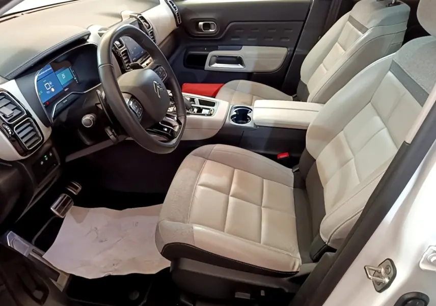 Vue intérieure côté conducteur du Citroën C5 Aircross Hybrid blanc, sièges bicolores et tableau de bord avec écran tactile.