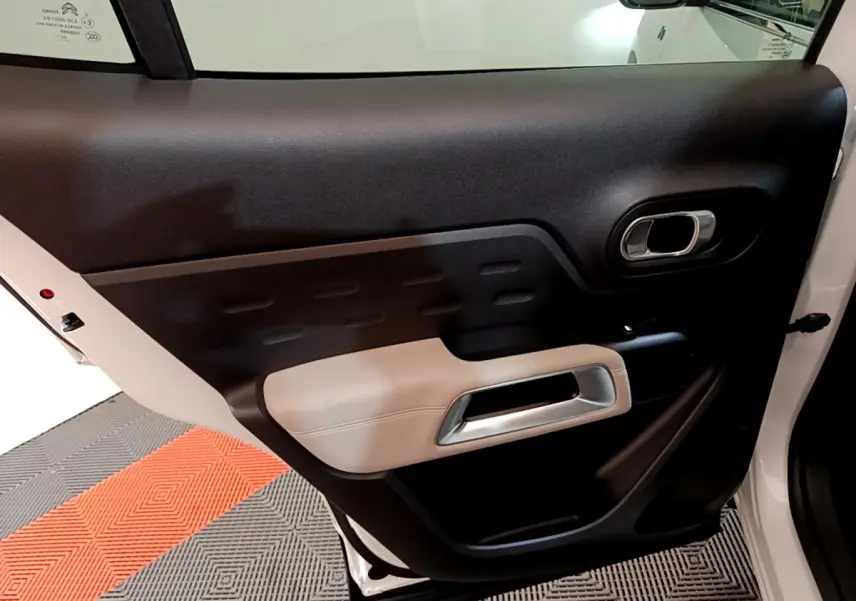 Vue intérieure de la porte arrière droite du Citroën C5 Aircross Hybrid blanc, avec garniture noire et beige.