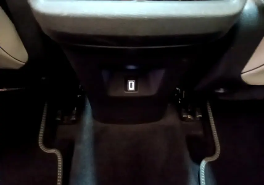 Vue rapprochée de la prise USB arrière entre les sièges noirs et beige du Citroën C5 Aircross Hybrid blanc.