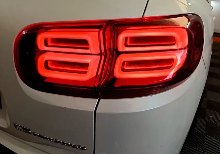 Gros plan sur le feu arrière droit rouge vif d’un Citroën C5 Aircross blanc, soulignant son design lumineux distinctif.