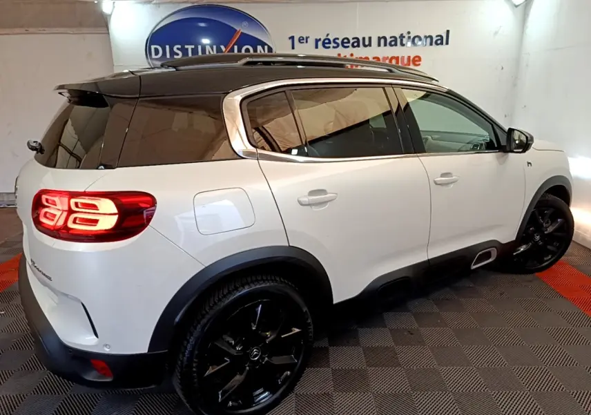 Vue 3/4 arrière droite du Citroën C5 Aircross Hybrid blanc avec toit noir et jantes noires brillantes.