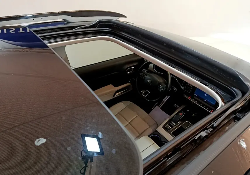 Vue plongeante sur l'intérieur beige et noir du Citroën C5 Aircross blanc via son toit ouvrant panoramique.