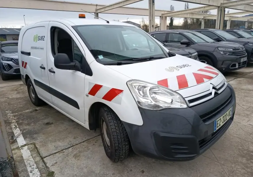 Vue 3/4 avant gauche d'un Citroën Berlingo blanc avec marquages rouges et logo Suez, équipé d'un gyrophare orange.