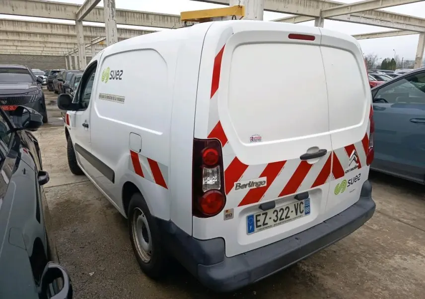 Vue 3/4 arrière droite d'un Citroën Berlingo blanc utilitaire avec bandes rouges réfléchissantes et logo Suez sur porte arrière.