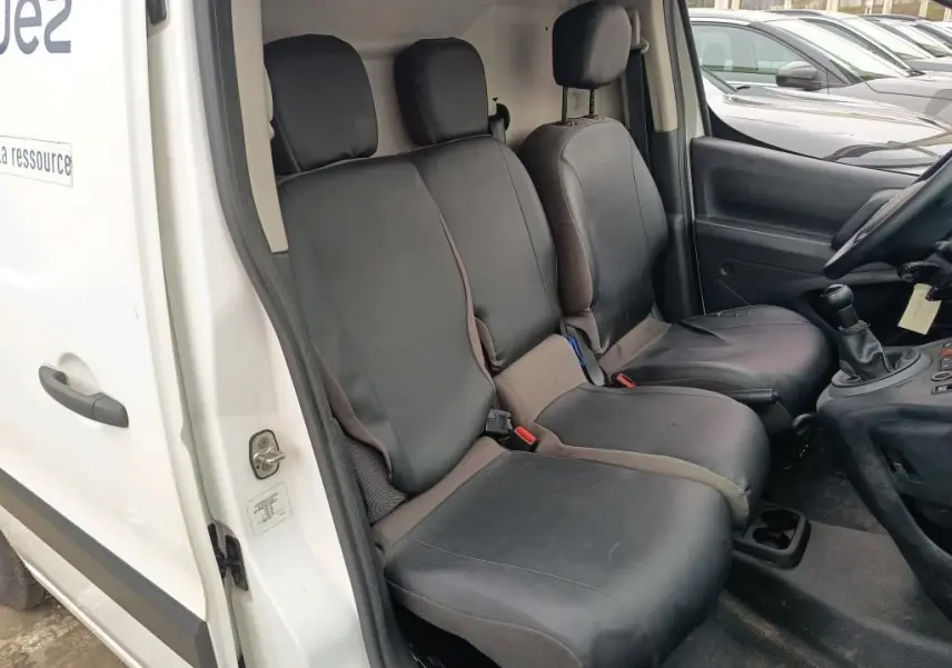 Vue intérieure côté conducteur du Citroën Berlingo blanc 2018, montrant les sièges avant en tissu noir et la boîte manuelle.